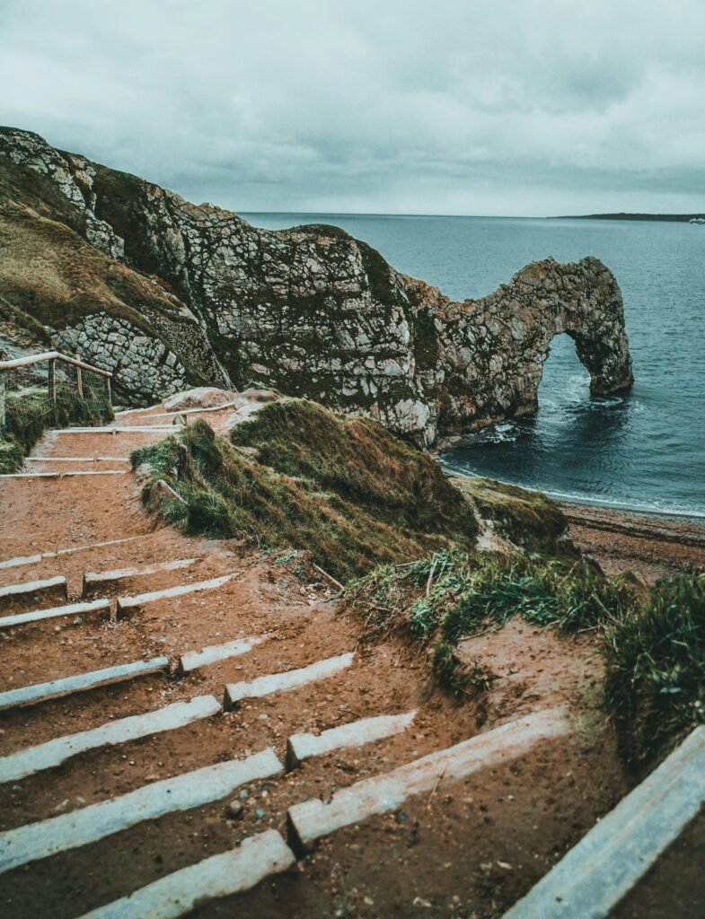 Pathway leading to the iconic Durdle Door rock arch at West Lulworth, UK, with a scenic coastal view.